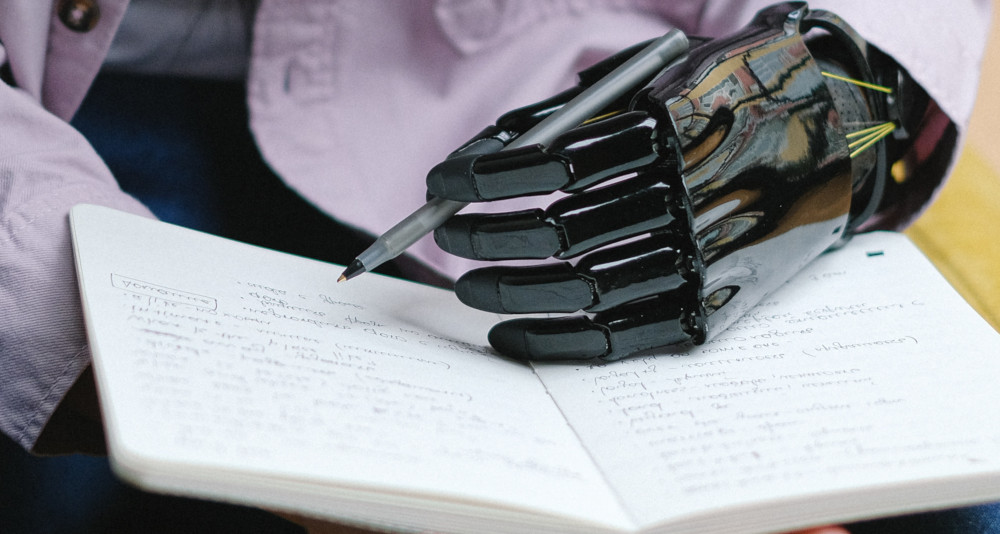 A human with robotic hand writing on a notebook,